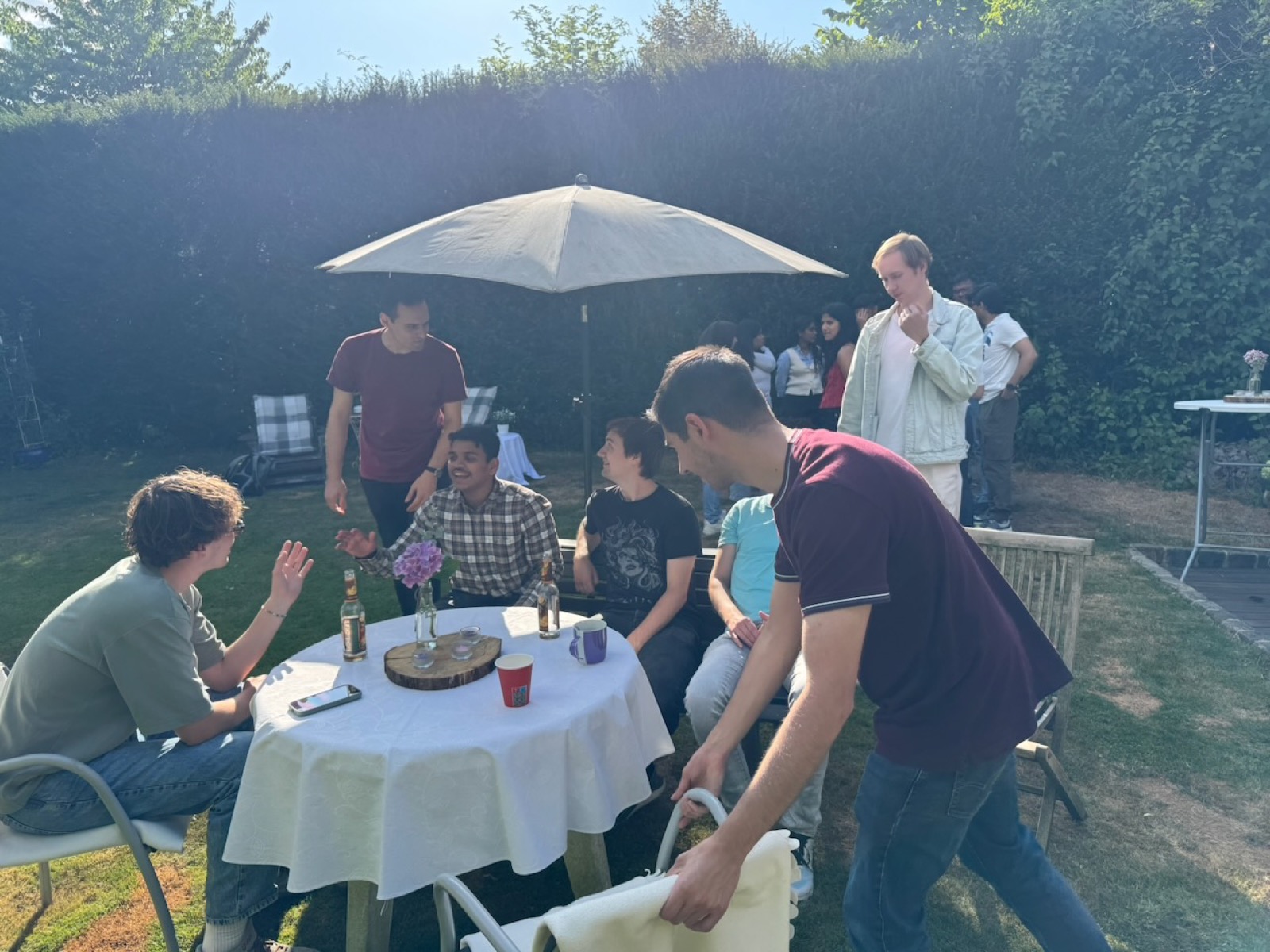 Students sitting together at a table in the garden during the garden party