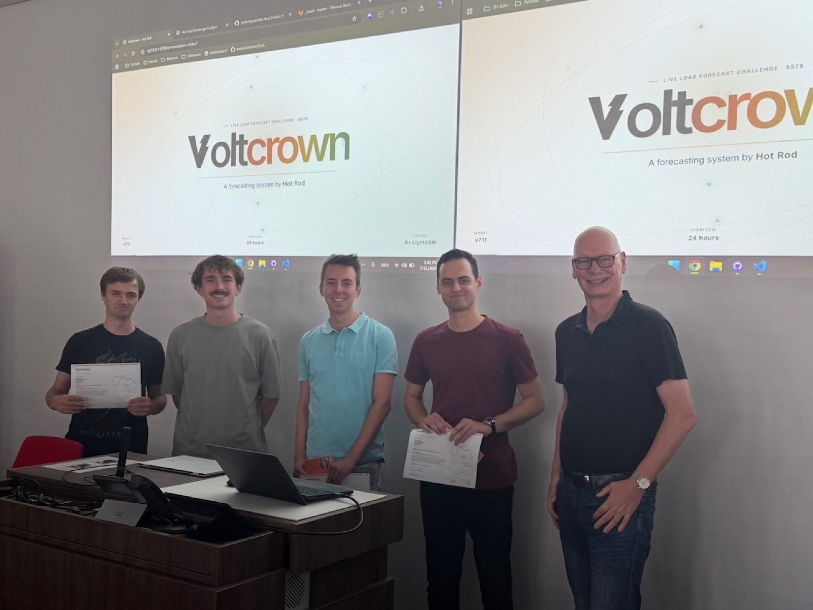 Four students of Team Hot Rod with Prof. Bartz-Beielstein in front of the presentation slides of their Voltcrown forecasting system