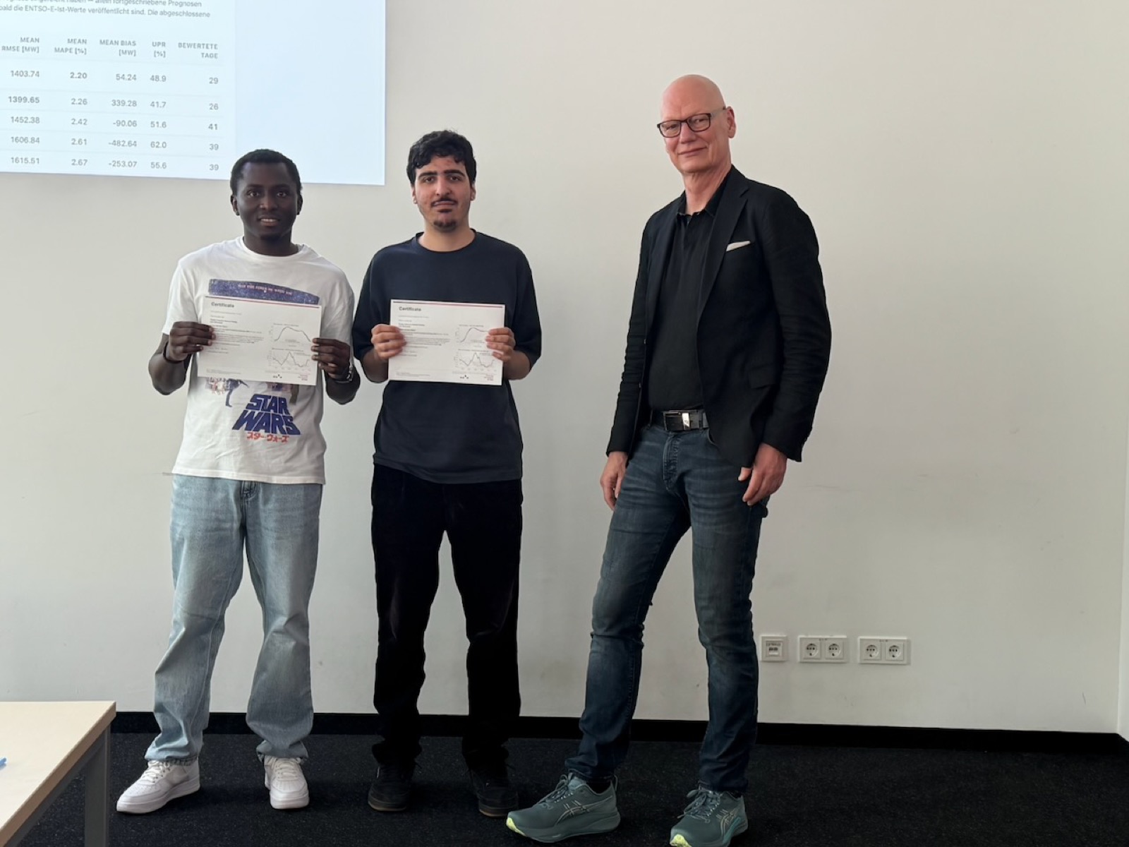 Two students holding their Load-Forecasting Challenge 2026 certificates