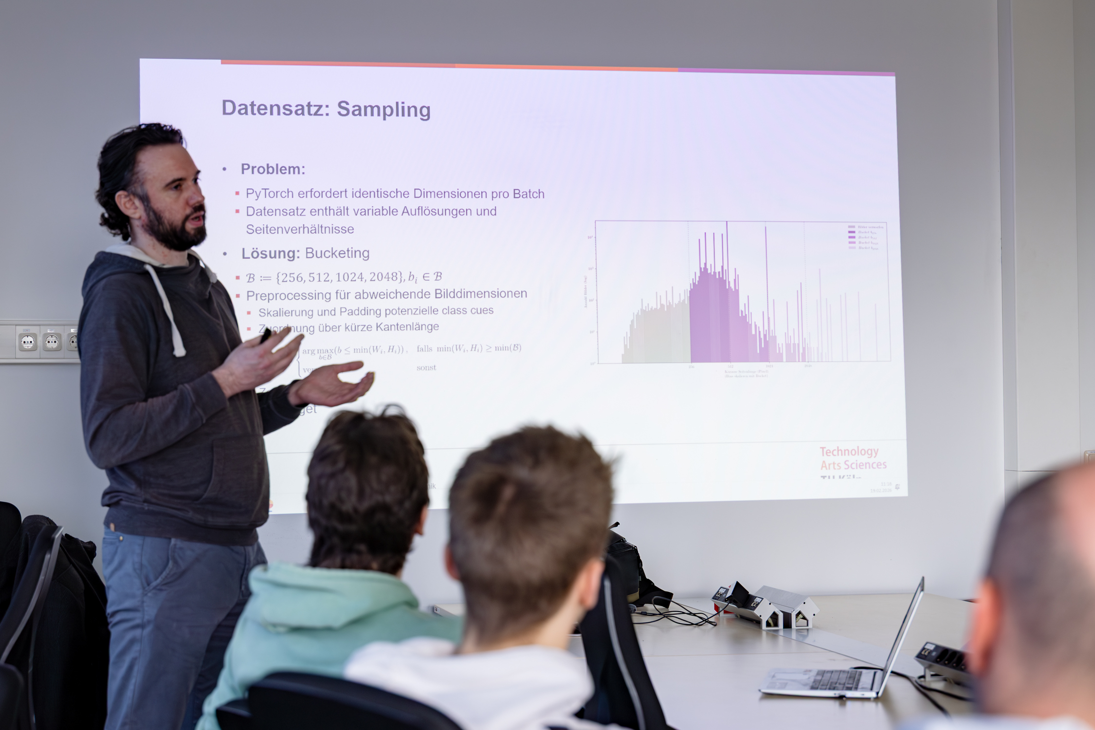 Vortragender vor der Titelfolie der Masterarbeit Tribraide